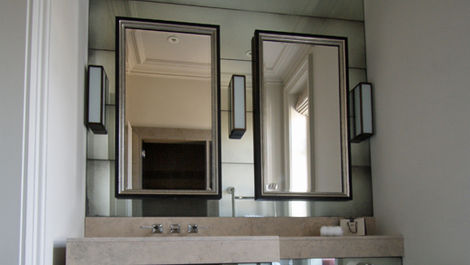 Shaped bevelled antique mirror on bathroom cabinet enhancing character and visual interest