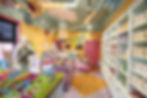 Colorful candy shop with vibrant decor, candy displays, and sign "Spin Your Own Cotton Candy." Employee at counter, cheerful atmosphere.