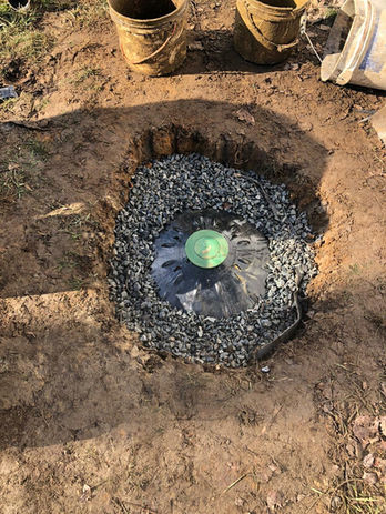 Dry well installation in a backyard with downspout extensions, and sump pump discharge line