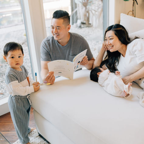 A family of four reading a book and cuddling on the couch