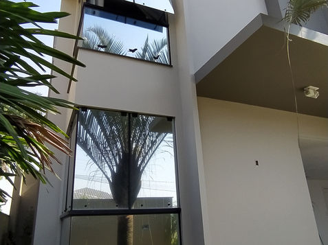 Fachada moderna de casa com janelas e detalhes arquitetônicos em dia ensolarado.