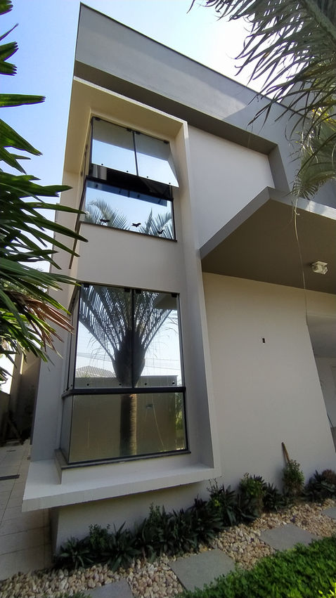 Fachada moderna de casa com janelas e detalhes arquitetônicos; vista externa.