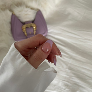 Eine Hand mit gemachten Doonails Nägeln und einer lila Tasche im Hintergrund