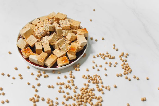 Tofu cubes sprinkled with sesame seeds on a white plate, a high calcium vegetarian food