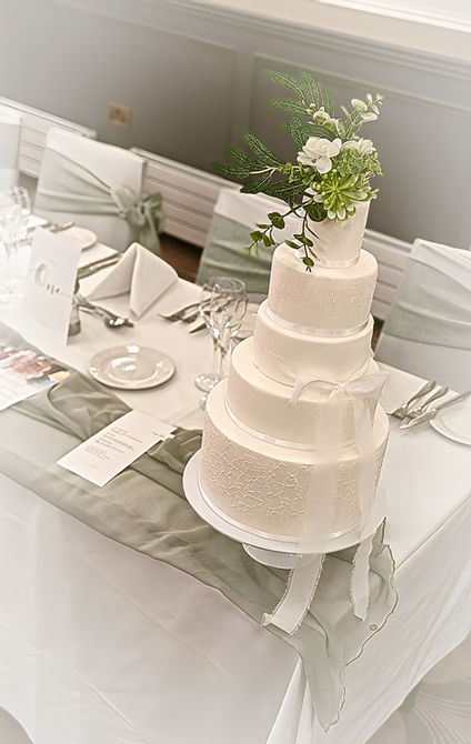 White wedding cake with subtle stencilling white ribbon bow