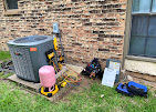 HVAC unit with tools, near a brick wall, servicing air conditioning. Fort Worth Air.