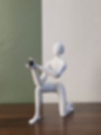 Knielend beeldje van een witte figuur die een ringdoosje aanbiedt