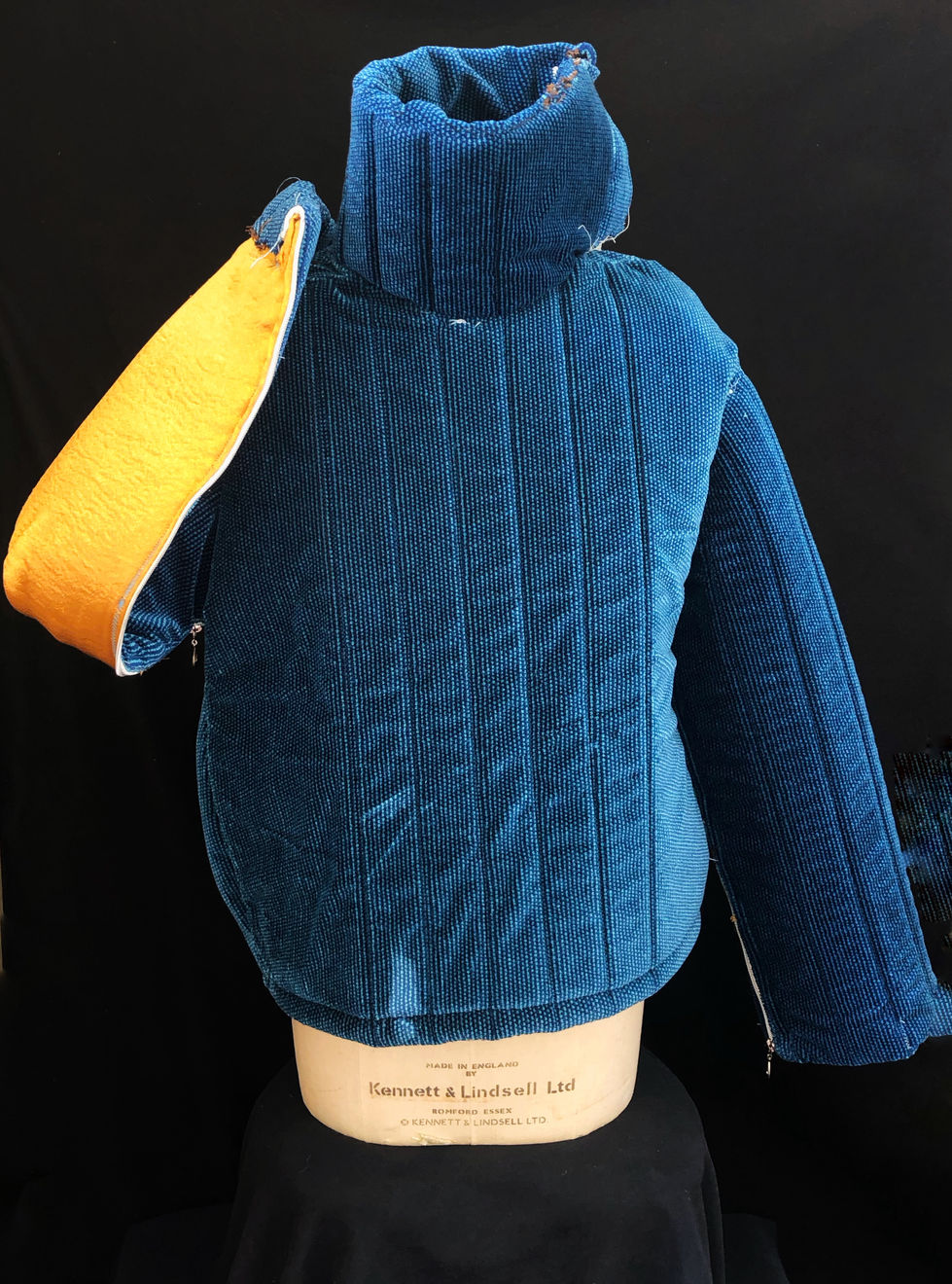 Manteau construit à partir d'un siège de cinéma issue du UGC Normandie. Manteau doublé de mousse et d'une doublure en satin or dans les manches. Zip le long des bras. Col haut avec ouverture en boutons.