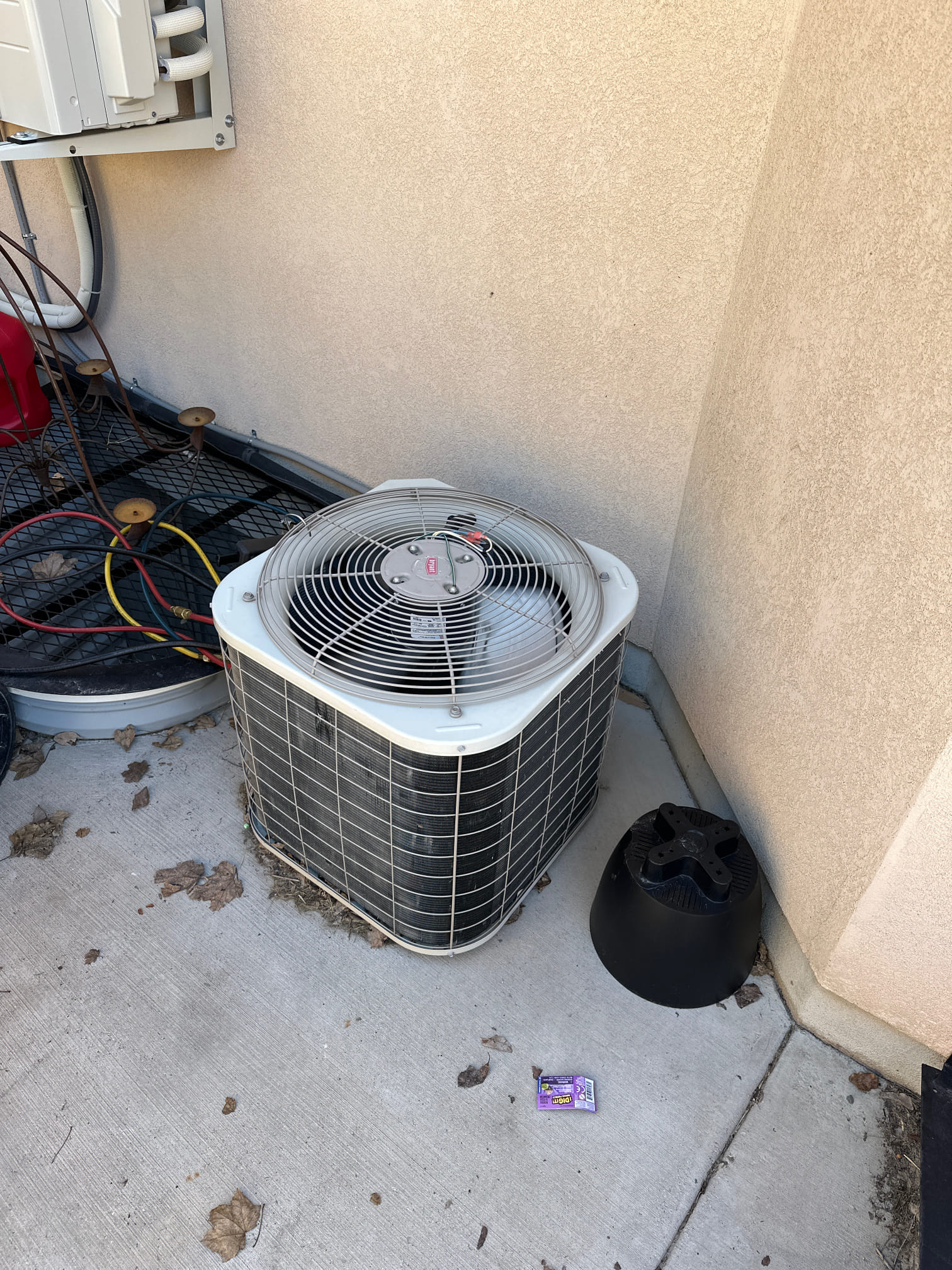 Close-up of a clean AC condenser fan spinning smoothly, implying efficient operation. Sunlight glints off the cool metal, suggesting the potential for refreshing, cold air. The unit's pristine condition hints at reliable performance and a comfortable indoor environment.