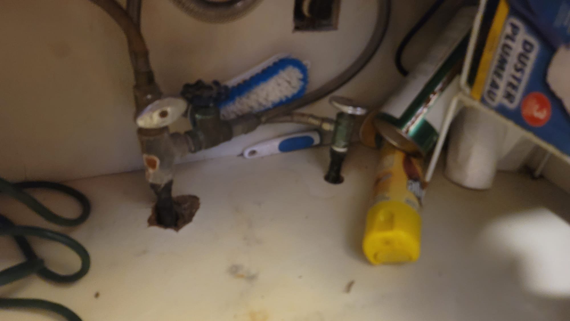 Close-up of a kitchen sink tap with a single, clear drop of water suspended at the tip, highlighting the need for a kitchen faucet filter to prevent mineral buildup that causes drips. Clean, uncluttered sink area emphasizes the benefit of a properly functioning, drip-free faucet, subtly suggesting solutions for 'how to fix a dripping faucet' to maintain a tidy and efficient kitchen.