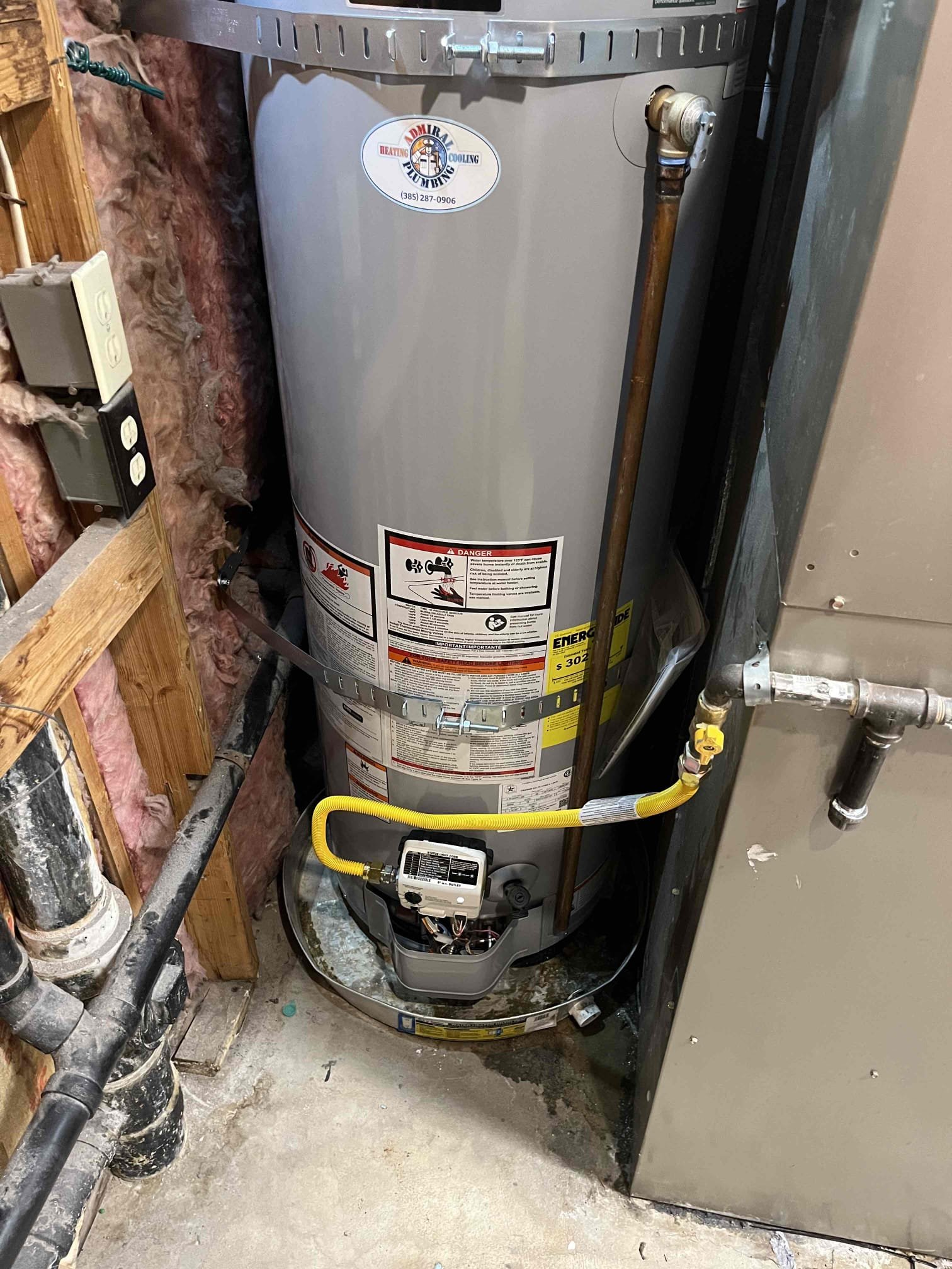 Sparkling, clear water flowing from a faucet, highlighting reduced scaling on a tankless water heater. A new, modern water softener is installed nearby, suggesting energy-efficient hot water thanks to soft water treatment and reliable water softener replacement.