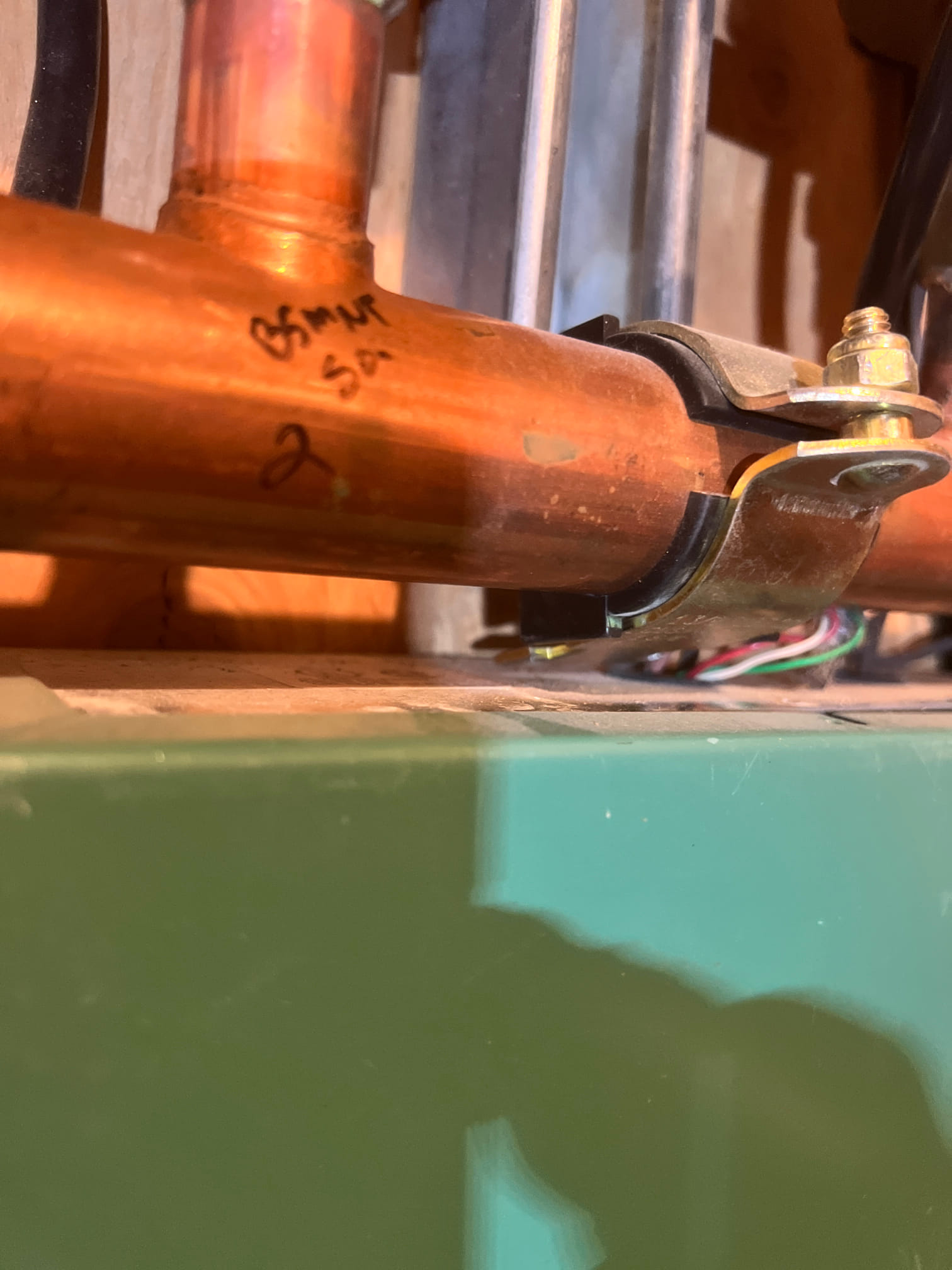 A split-level home with a geothermal unit partially visible in the yard, showcasing energy efficiency. Sunlight glints off solar panels on the roof. An inset image displays a family comfortably relaxing indoors, illustrating the benefit of affordable, year-round climate control.