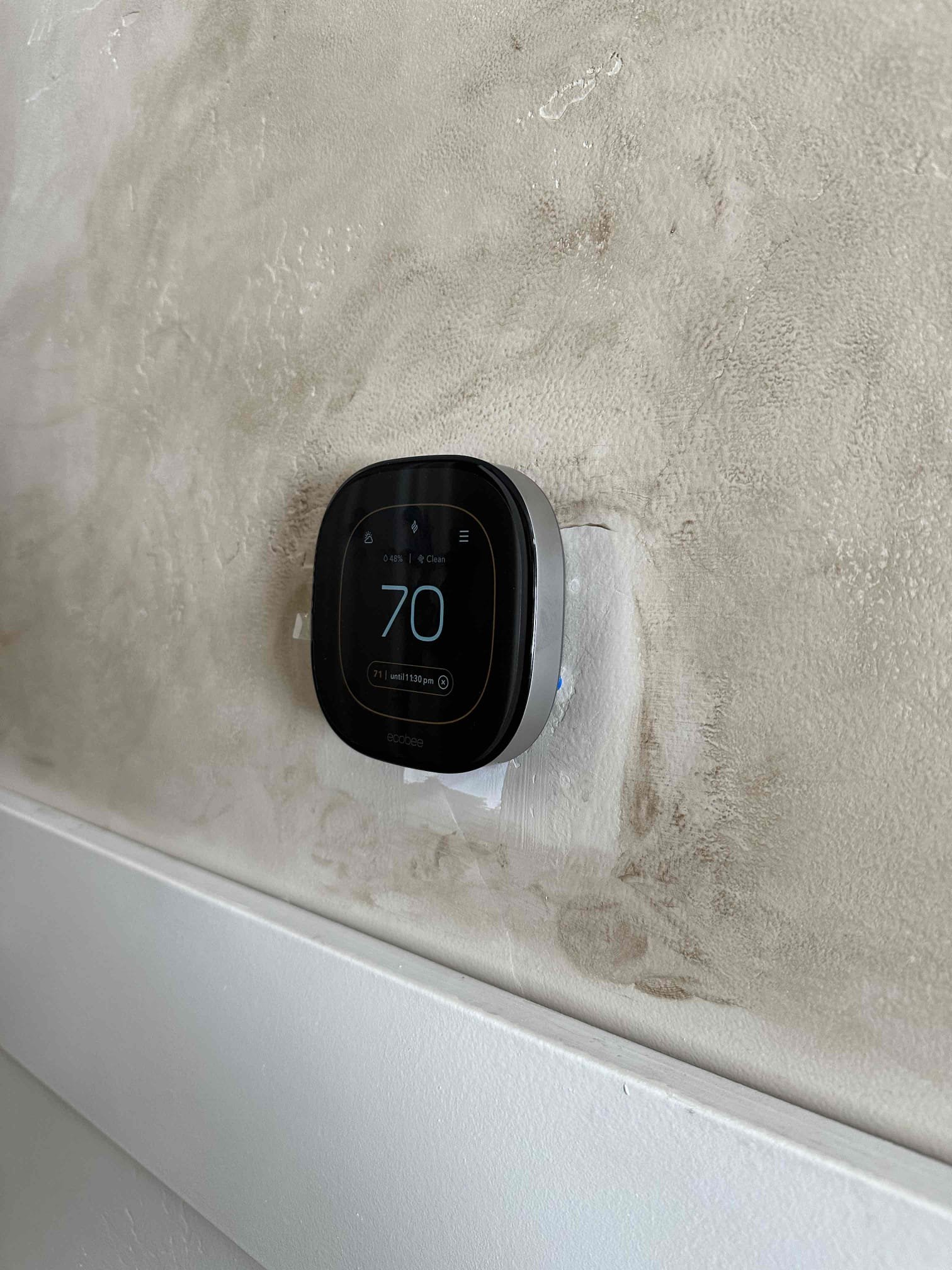 A close-up shot of a modern Bluetooth thermostat, highlighting its sleek design and user-friendly interface. The screen displays an error message about the furnace not turning on, but a hand is shown easily accessing troubleshooting options via a smartphone app, emphasizing the convenience and control offered by smart thermostats compared to traditional shop thermostats.