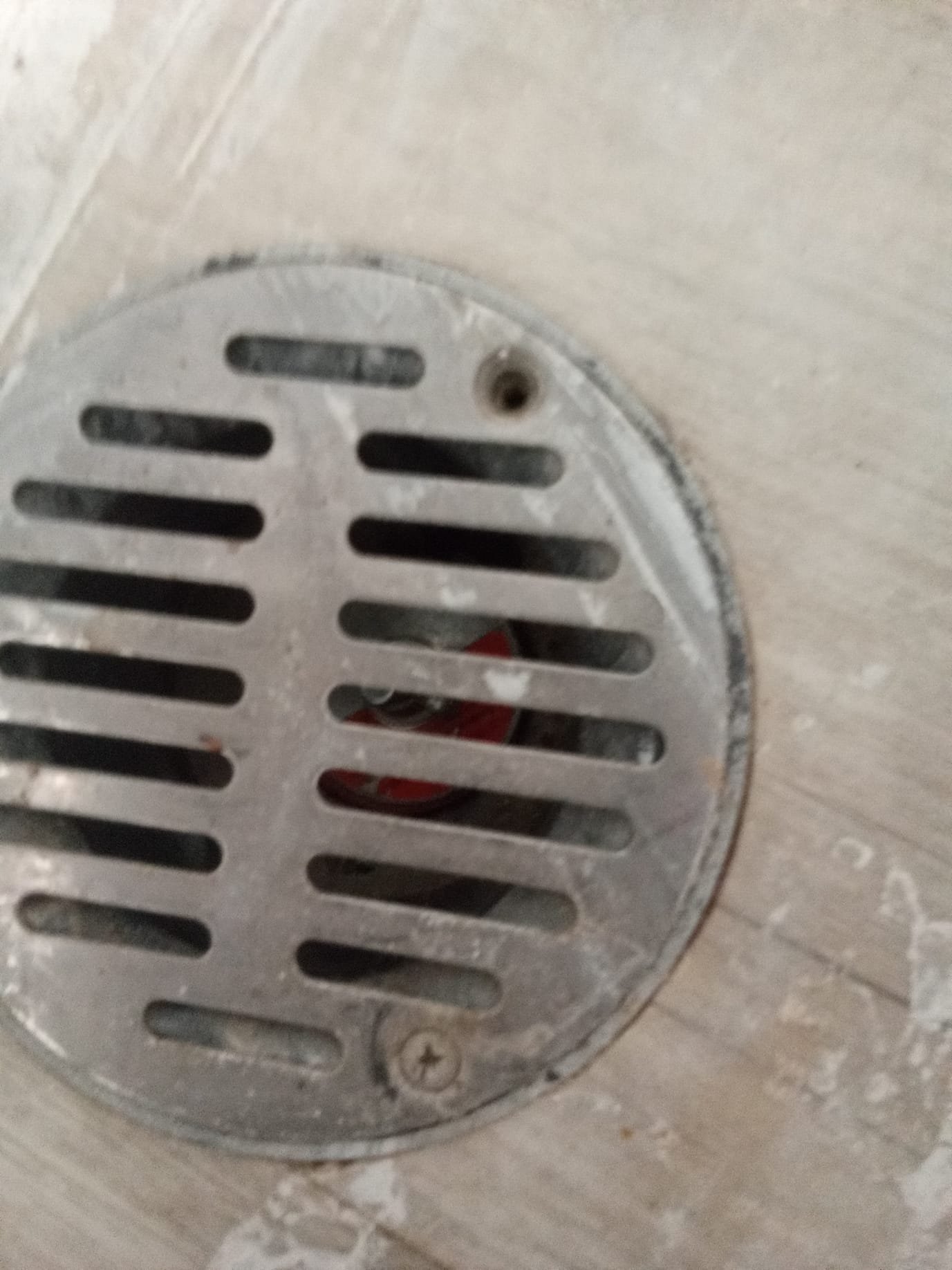 Metal floor drain on a patio, showcasing efficient water runoff. Its design hints at a solution for clogged drains, suggesting easy maintenance and prevention of water buildup. A clean, dry patio surface highlights the drain's effectiveness.