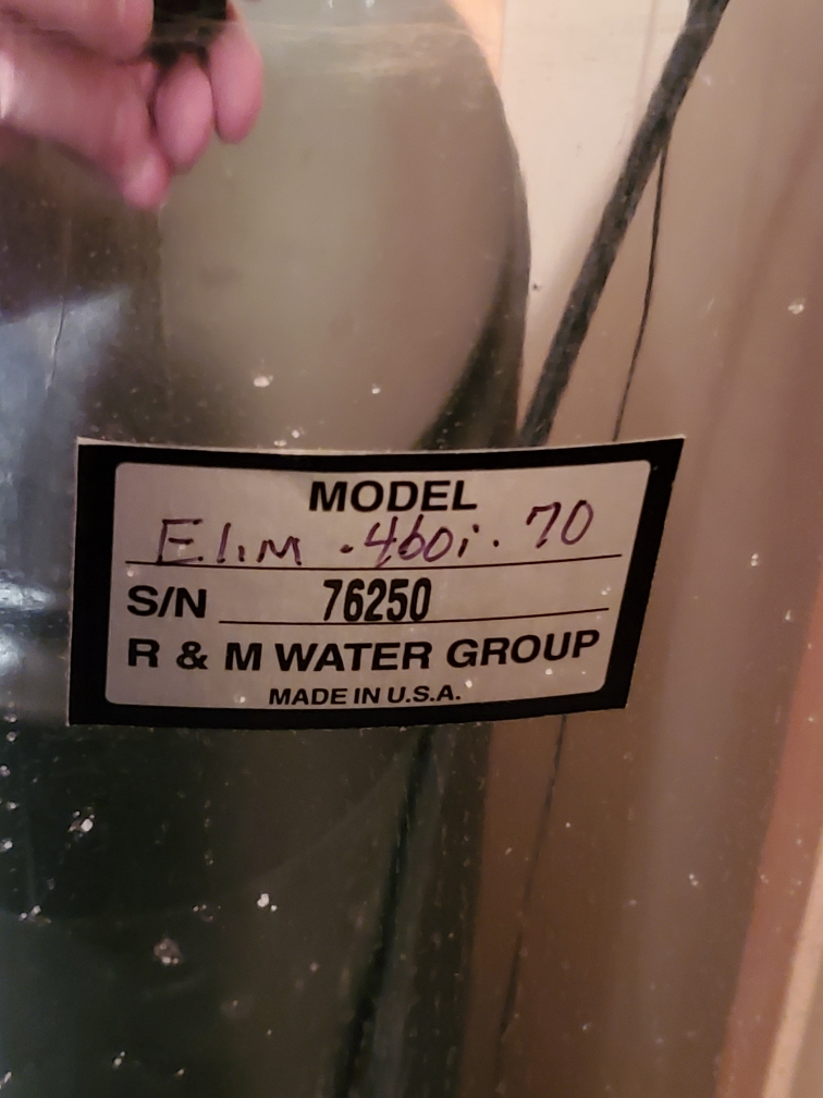 Water softener system, newly installed as part of a water softener clearance sale, sits beside a gleaming hot water heater replacement in a Woods Cross, Utah home. Clean, softened water benefits are visually suggested by spotless fixtures and healthy plant life.