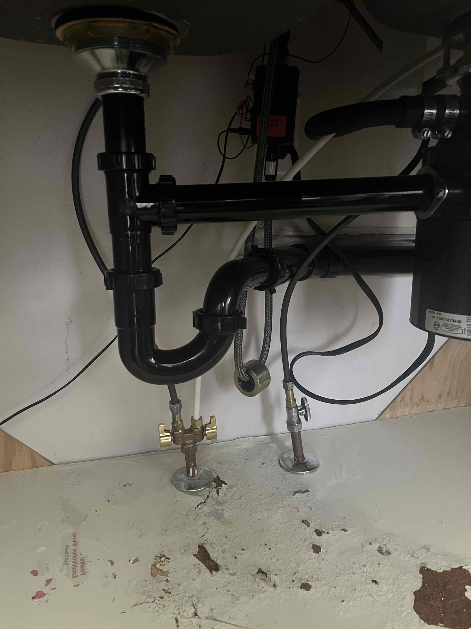 Image shows a homeowner confidently resetting their garbage disposal with easy-to-follow steps, implying quick fixes and reduced disaster restoration costs. Bright kitchen setting suggests a return to normalcy after a potential disaster.