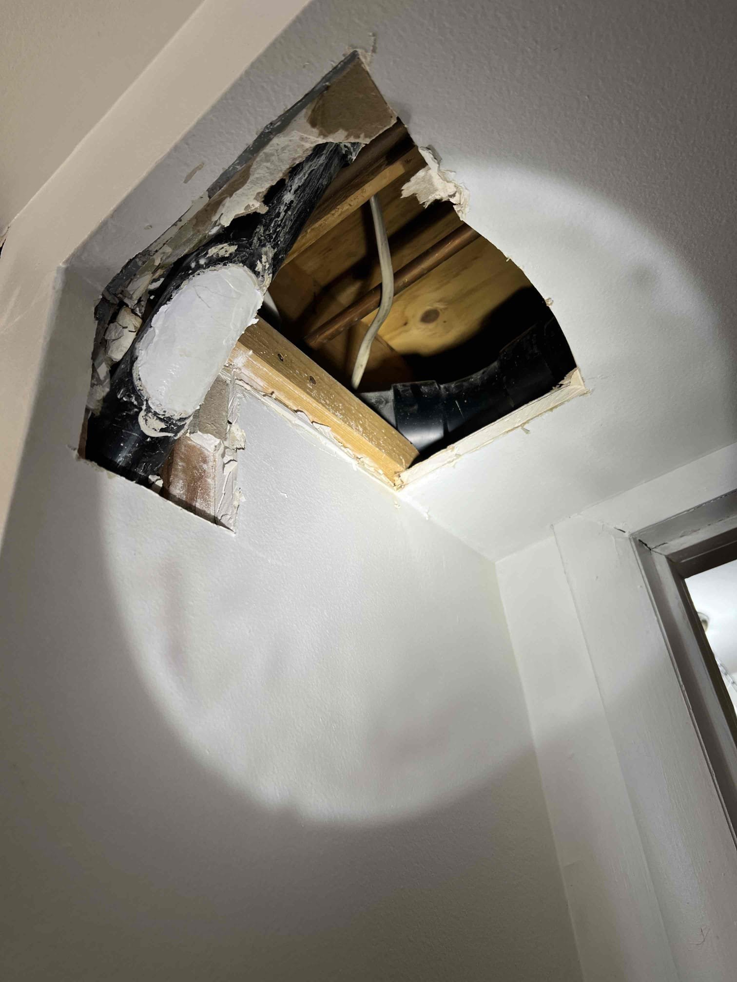 Damp basement ceiling with water stains and mold growth around a vent, suggesting potential water damage. Addressing this promptly with a basement ceiling water damage service can prevent further structural issues and improve air quality.