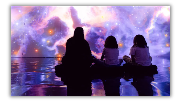 Visitors seated before an immersive display of stars and colorful nebulae.