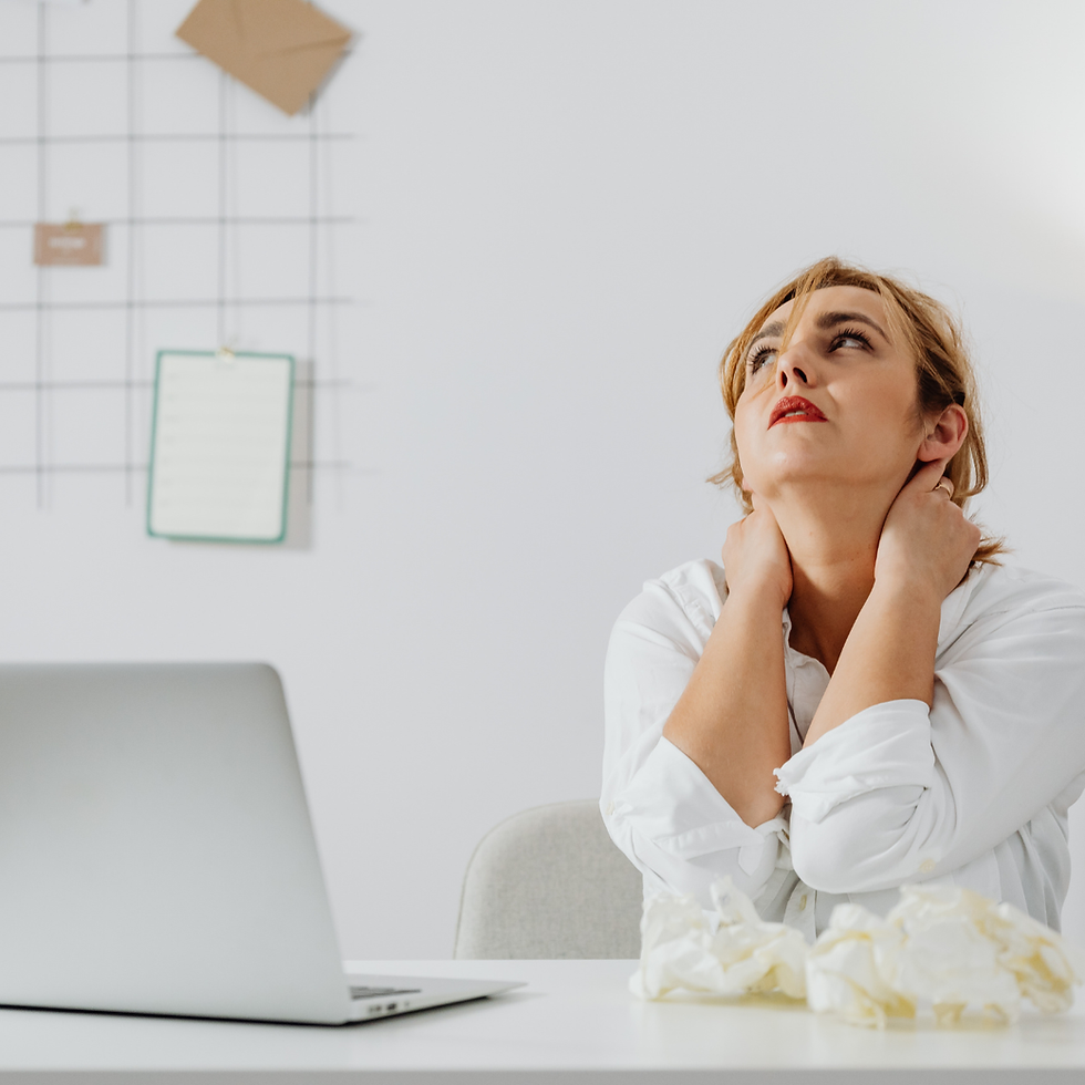 Employee at a desk showing early signs of neurodivergent burnout, tired and holding her neck