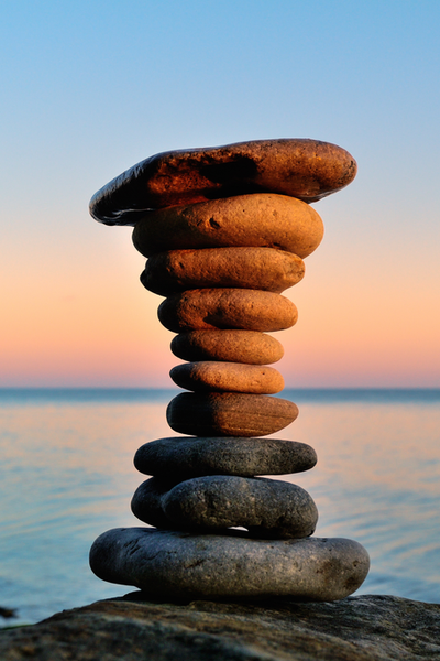 Stacked stones balanced against a sky and water background