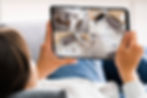 Lady lying on couch viewing CCTV cameras on tablet app