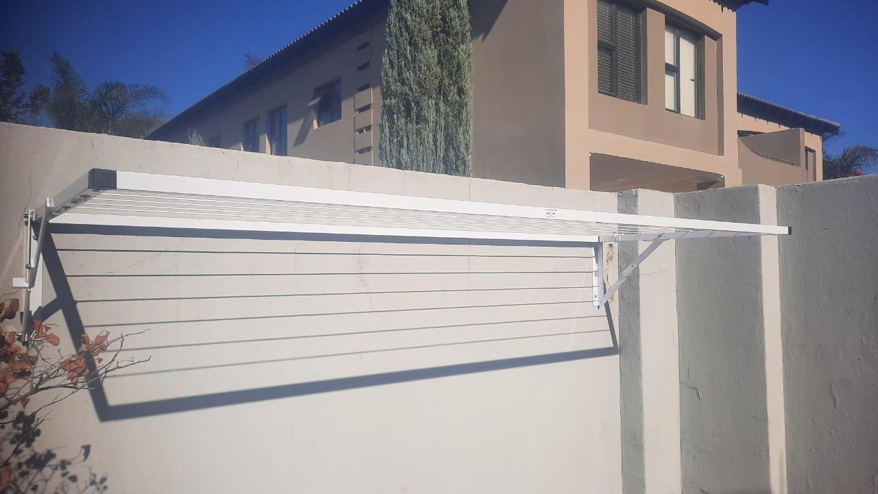 White foldaway washing line mounted on a beige plaster wall
