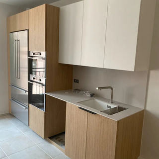 Une cuisine moderne avec des meubles en bois clair, un évier et Jfp Renovation.