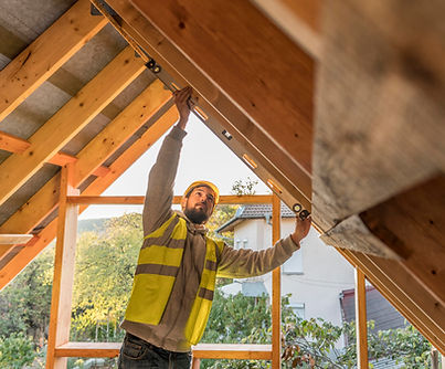 Un travailleur avec un gilet de sécurité dans un grenier en construction. Jfp Renovation
