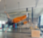 Mand hænger på stang, orange bukser, grå trøje, Personlig Tr. Træningslokale baggrund. Humanflag