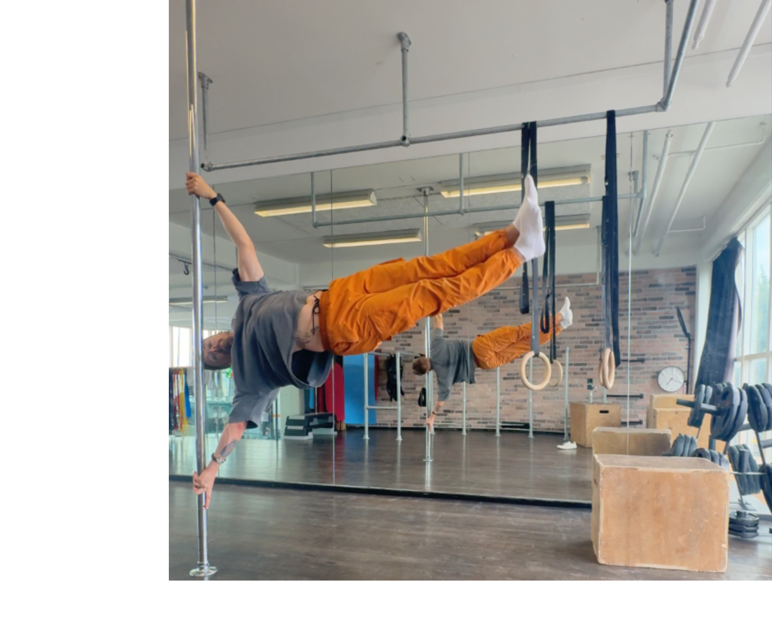 Mand i orange bukser laver flag på stang i fitnesscenter. Personlig træning.