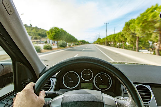 Photo of a car driving down the road from the perspective of the driver. The road is straight, trees line the street and it is sunny out. This relates to the post because it talks about tracking your business mileage.
