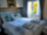 Double bed with throw, pillows and bath towels folded on top