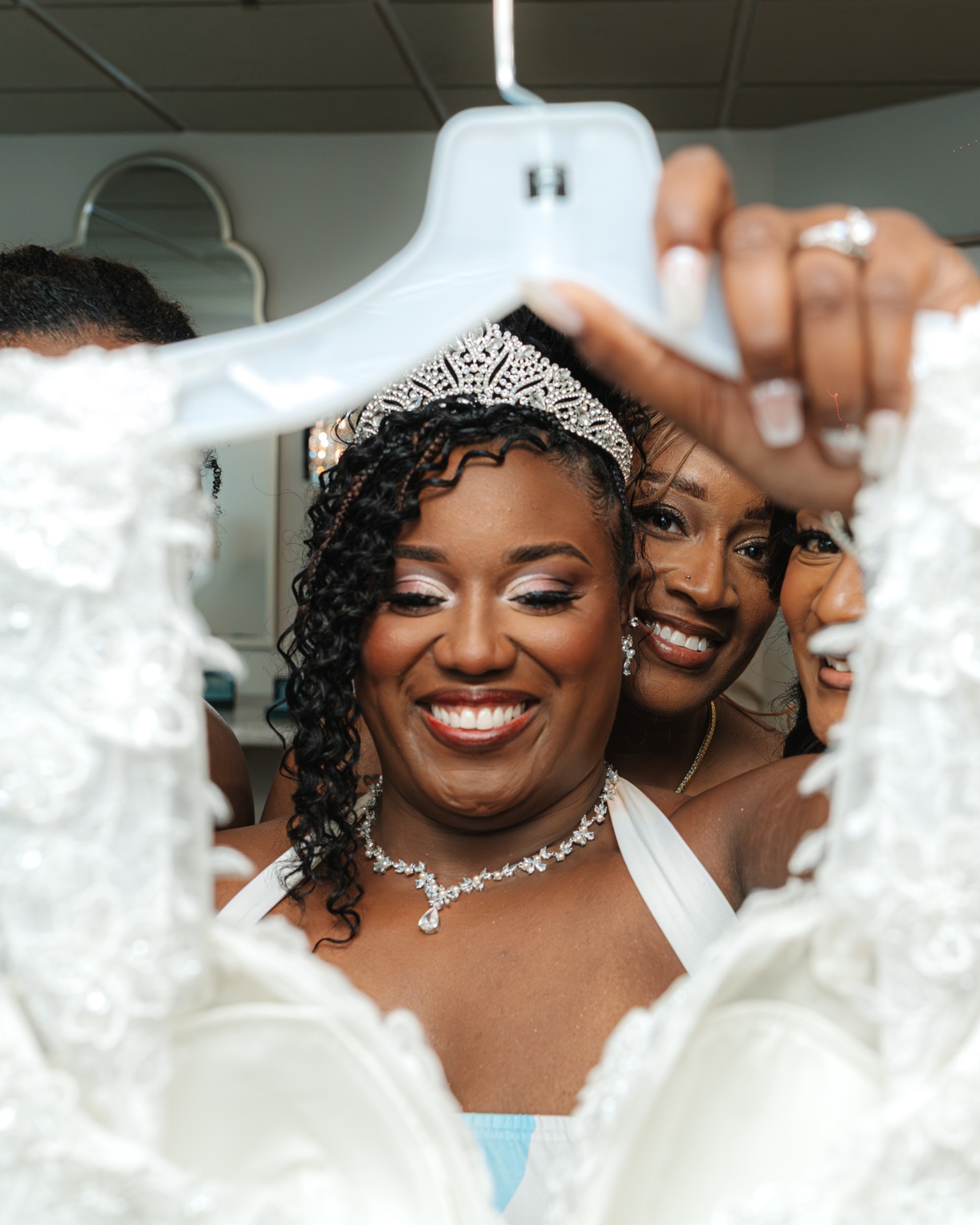 Ramarra smiling behind her wedding dress hanger.