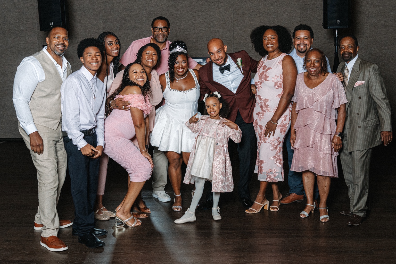 Ramarra and Evan posing with family and guests in pink and blush at their reception.