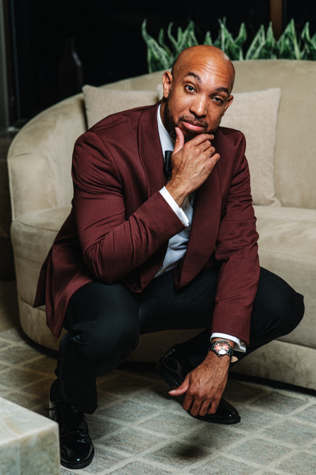 Editorial portrait of Evan leaning forward in his burgundy wedding tuxedo.