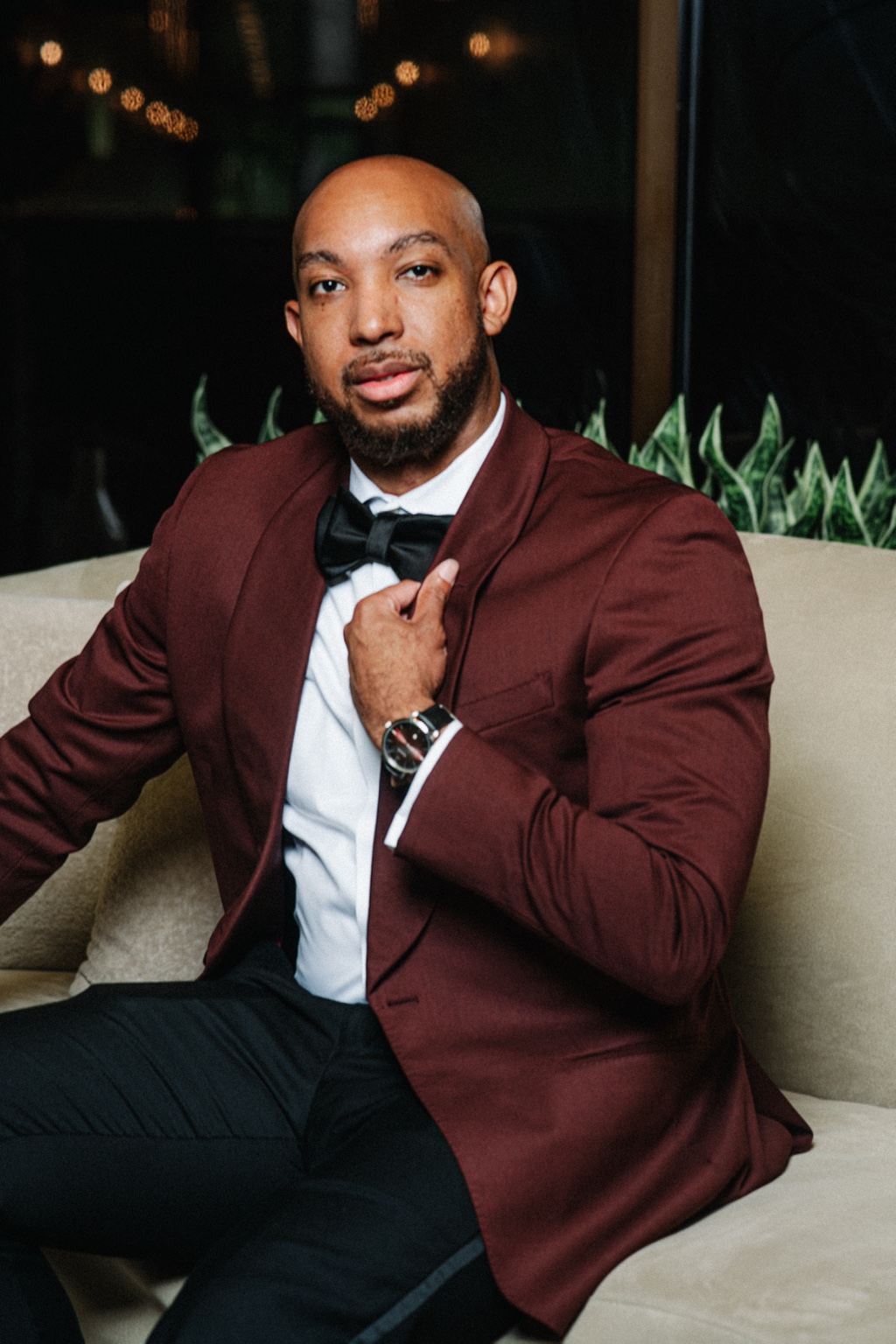 Portrait of Evan holding his lapel in a burgundy tuxedo at Laurel Manor.