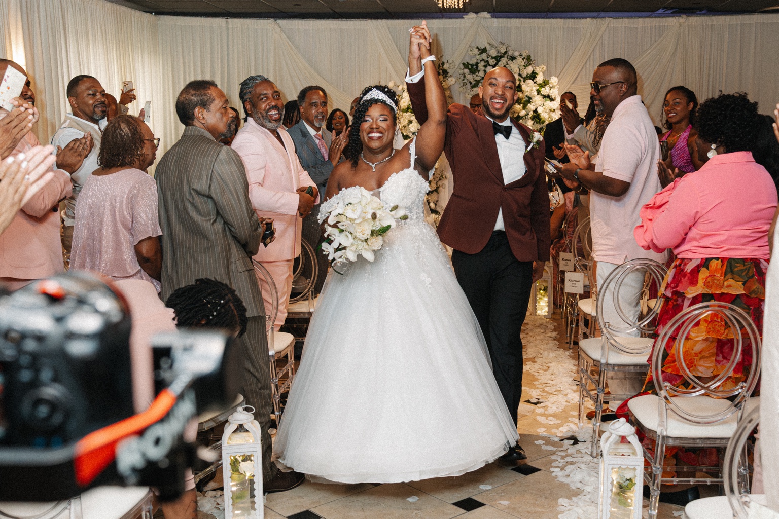 Ramarra and Evan raising their hands as guests cheer after their wedding ceremony.
