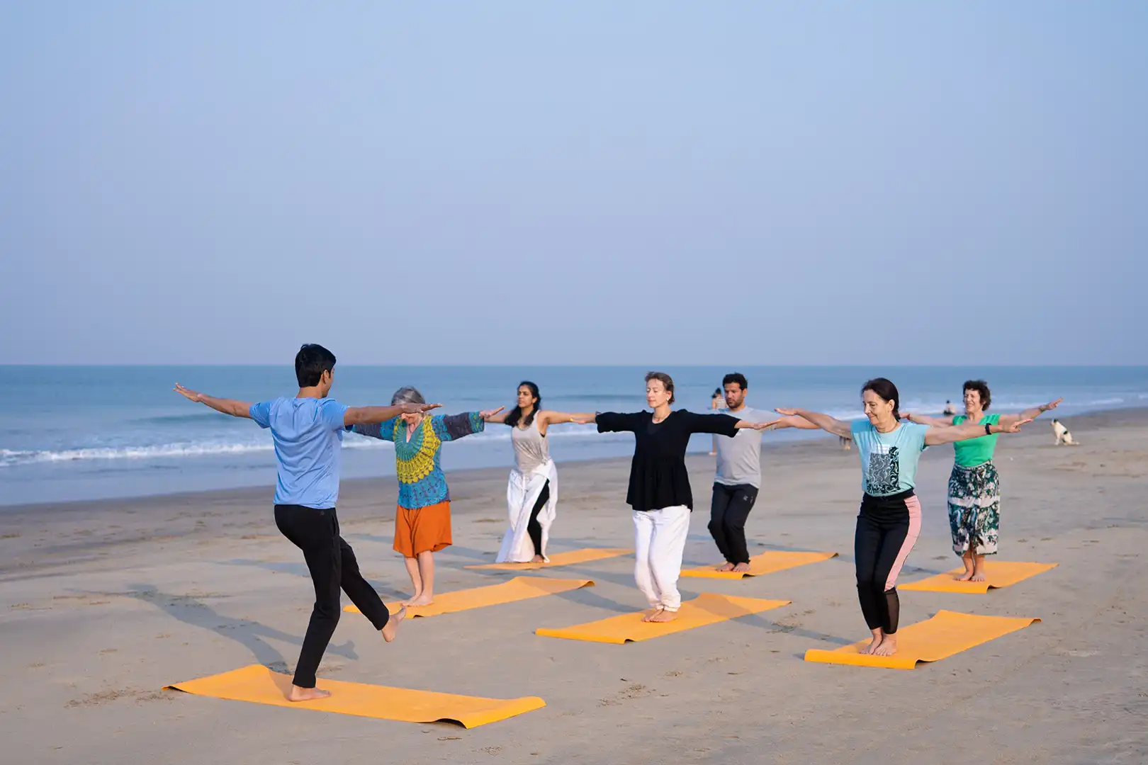 rohan shroff from satvan yoga, goa conducting a beach yoga session with group of students