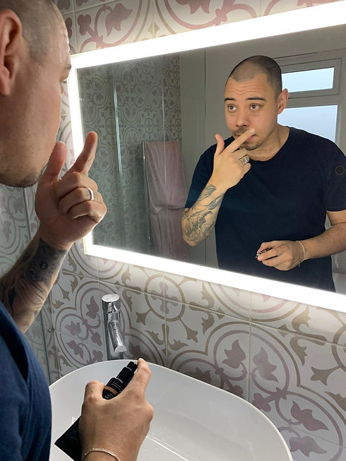 Man appling makeup in mirror