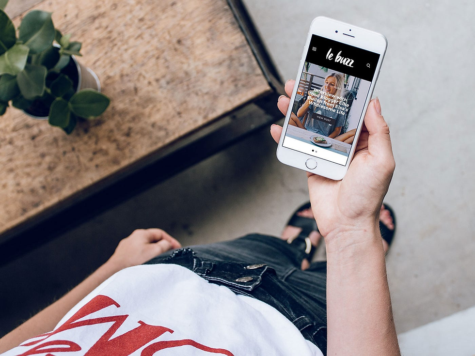 Person holds a smartphone showing "a web page. Casual setting, wooden table, plant.