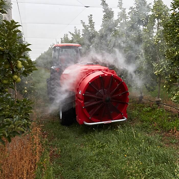 Air-blast sprayer delivering a fine foliar mist through the orchard canopy.