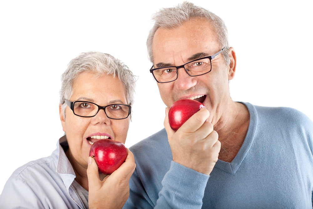 Pareja mayor mordiendo una manzana