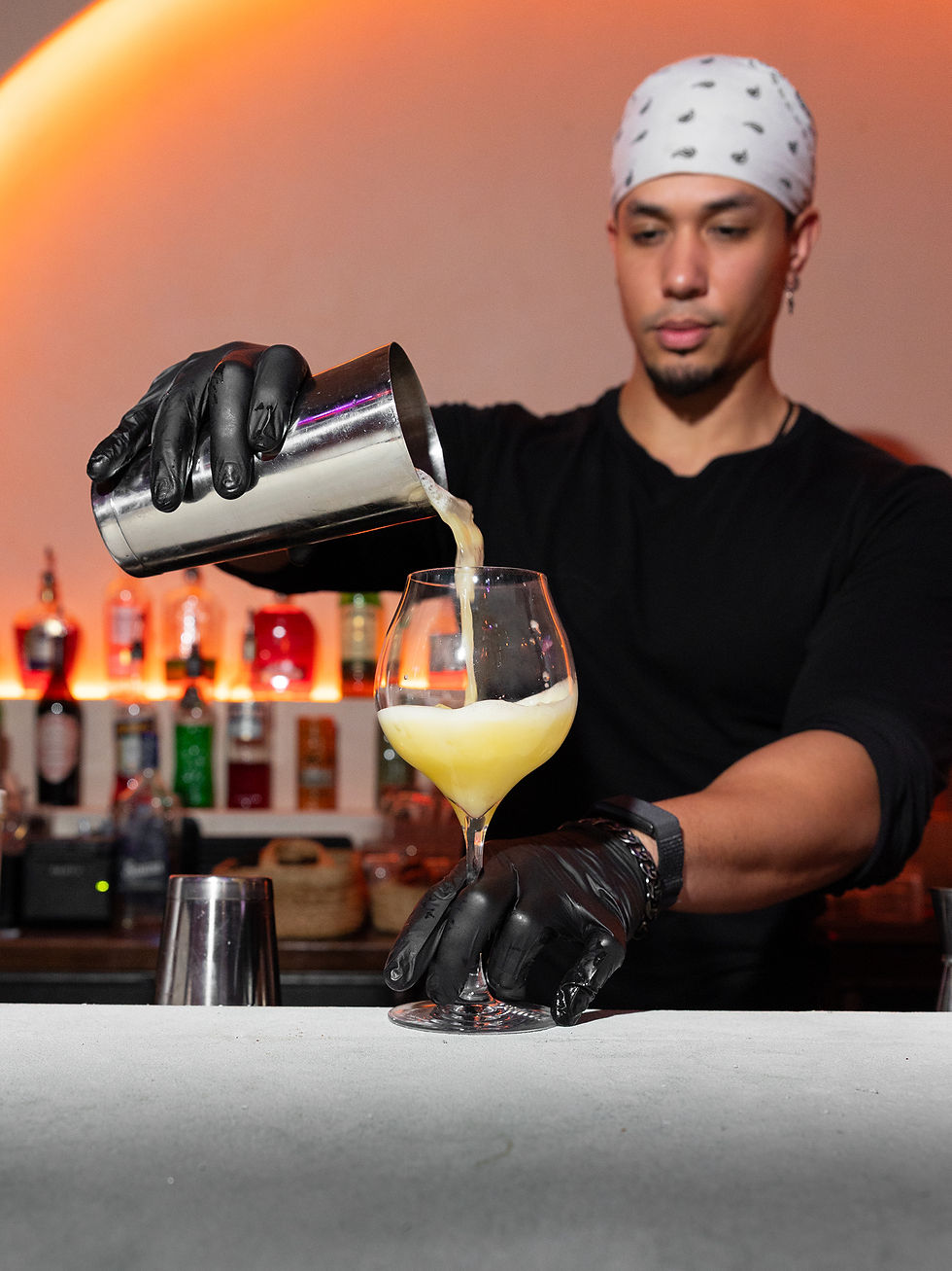 Close-up view of a bartender pouring a colorful cocktail with fresh ingredients