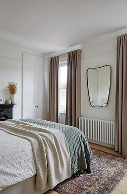 A curved mirror brings a touch of mid-century style. Pink floor length curtains