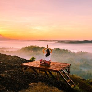 Femme faisant du yoga devant un paysage majestueux.