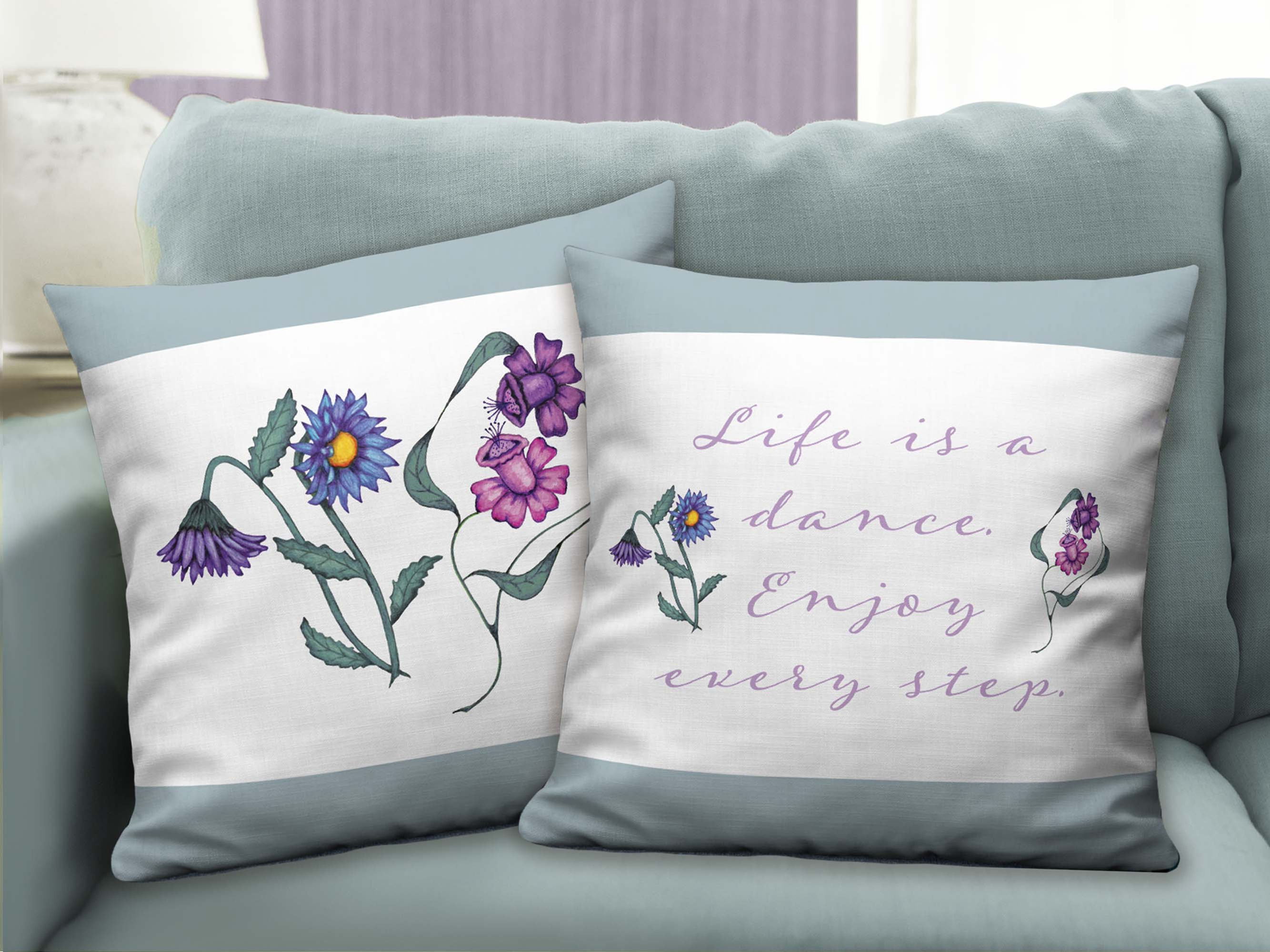 Two 22”x22” Dancing Flowers throw pillows on light green couch. Front side (flowers). Back side (life is a dance quote).