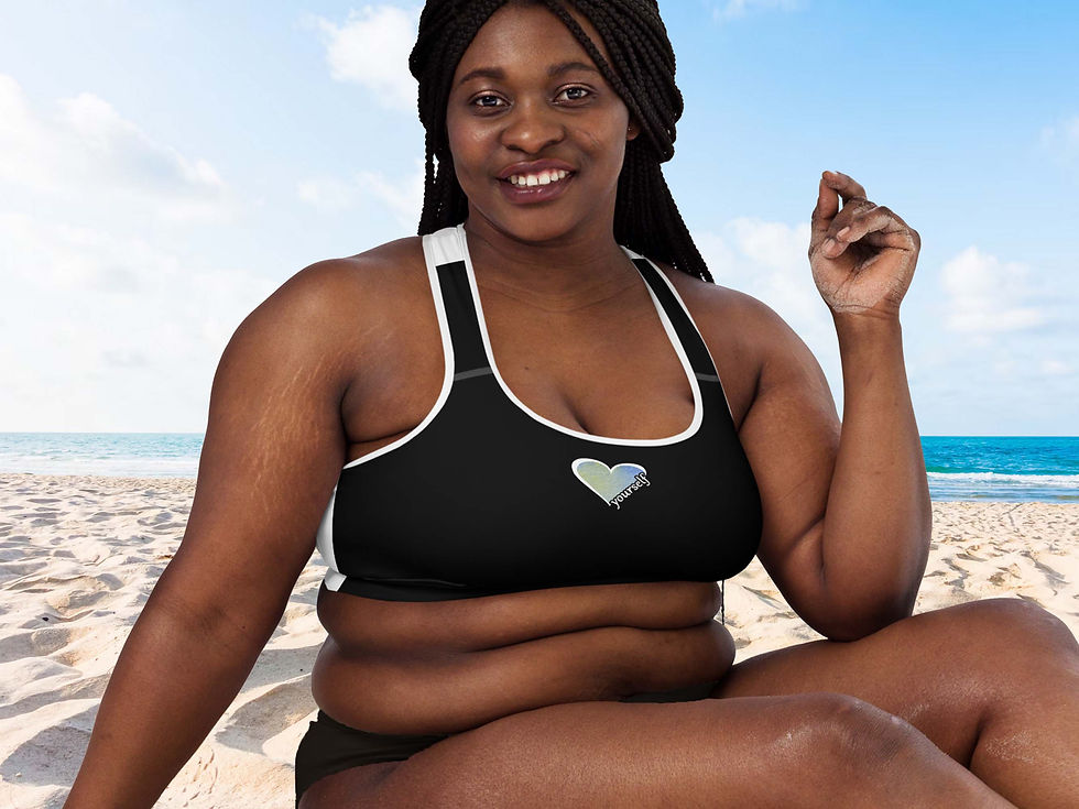 Thumbnail: Plus size woman sitting on a sandy beach. She’s wearing a black Love Yourself sports bra and black swimsuit bottom.