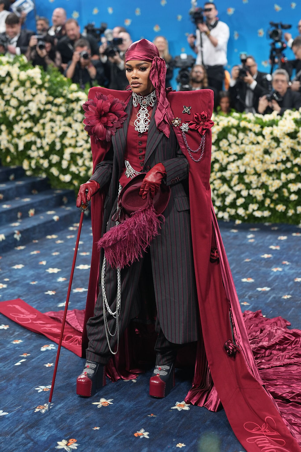 Teyana Taylor, in collaboration with costume designer Ruth E. Carter, the first African-American to win an Academy Award Best Costume Design, arrived at the Met Gala in a stunning burgundy get-up. On her cape, the phrase “Rose in Harlem” is embroidered in looping letters.