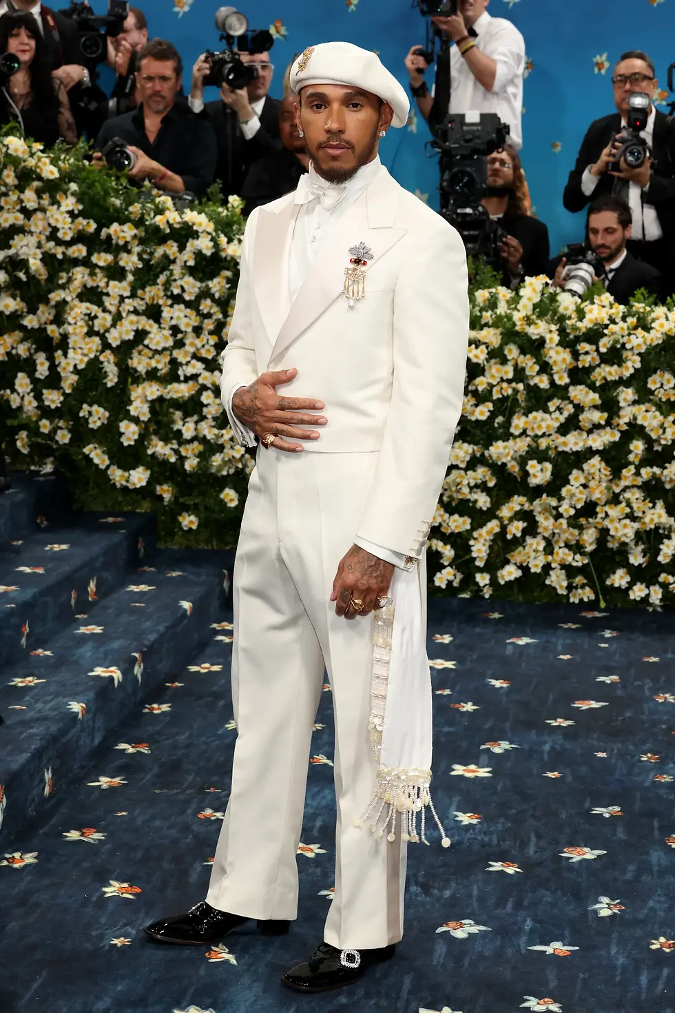 British Formula One Driver and Seven-Time World Driver’s Champion Lewis Hamilton, whose sash is lined with cowrie shells, a protective talisman in African culture.