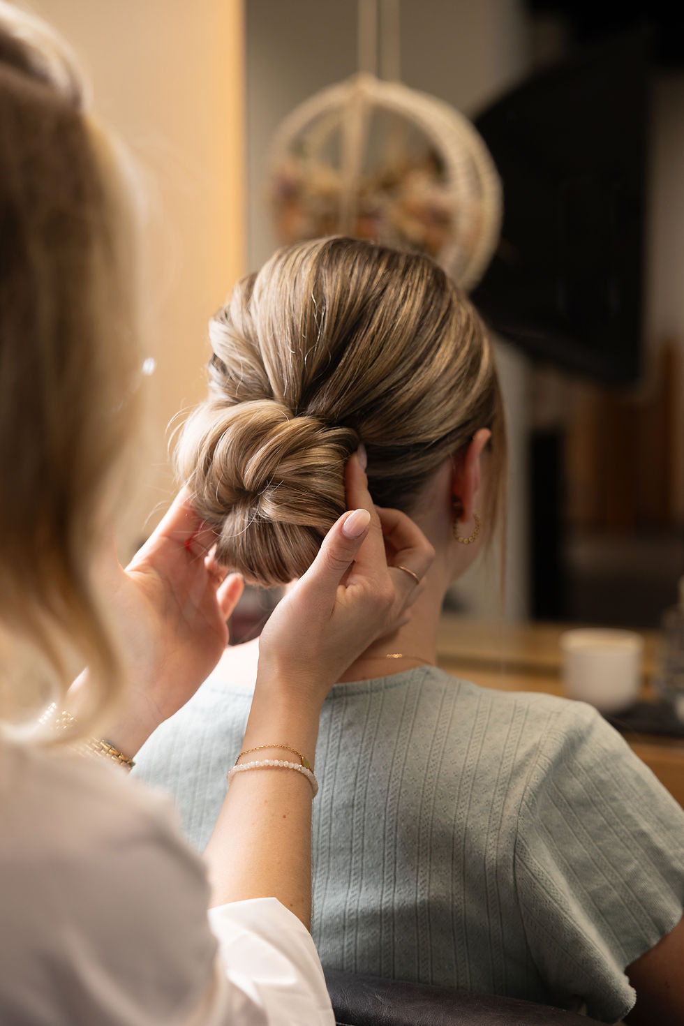 Stylistin steckt Frisiernadeln in eine Hochsteckfrisur einer Kundin